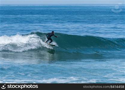 Surfer riding waves with a short board in Furadouro beach, Portugal. Men catching waves in ocean. Surfing action water board sport.