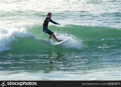 Surfer riding waves with a short board in Furadouro beach, Portugal. Men catching waves in ocean. Surfing action water board sport.