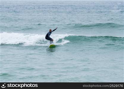 Surfer riding waves with a soft board in Furadouro beach, Portugal. Men catching waves in ocean. Surfing action water board sport.