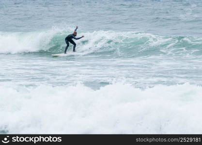 Surfer riding waves with a soft board in Furadouro beach, Portugal. Men catching waves in ocean. Surfing action water board sport.