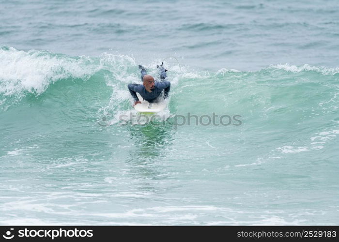 Surfer riding waves with a soft board in Furadouro beach, Portugal. Men catching waves in ocean. Surfing action water board sport.