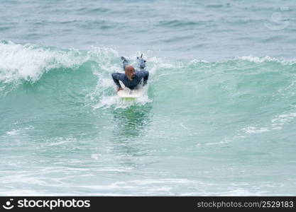 Surfer riding waves with a soft board in Furadouro beach, Portugal. Men catching waves in ocean. Surfing action water board sport.