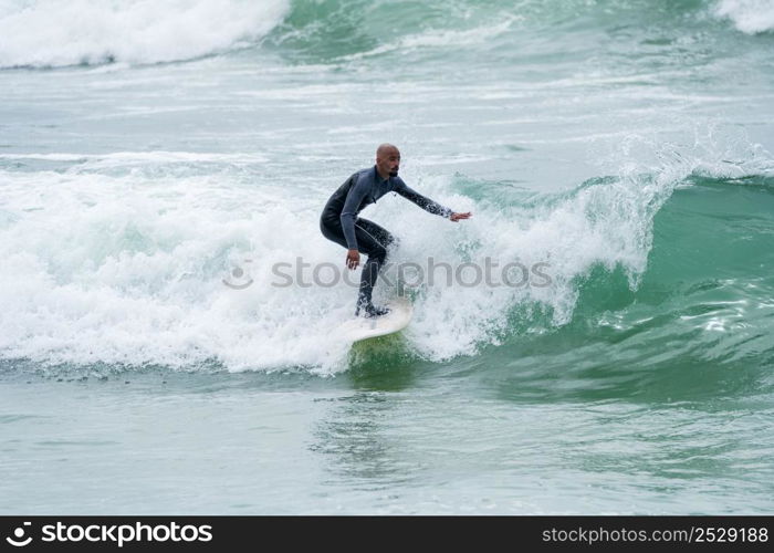 Surfer riding waves with a soft board in Furadouro beach, Portugal. Men catching waves in ocean. Surfing action water board sport.