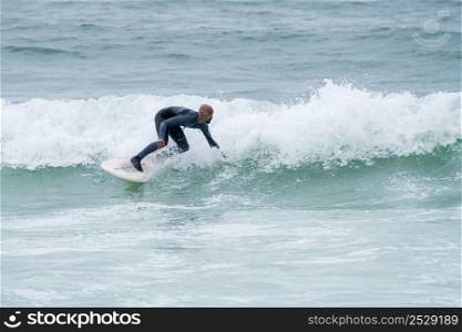 Surfer riding waves with a soft board in Furadouro beach, Portugal. Men catching waves in ocean. Surfing action water board sport.