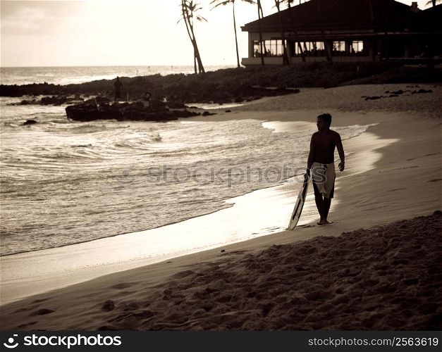 Surfer walking along coastline