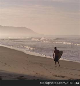 Surfer walking down beach