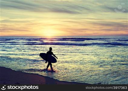 Surfer walking on the beach at sunset. Vintage color