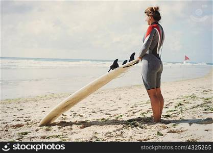 Surfer with surfboard on beach, Lacanau, France