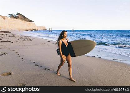 Surfer with surfboard on beach, Santa Cruz, California, USA