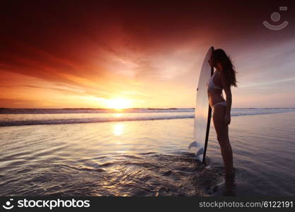 Surfer woman on beach at sunset. Beautiful surfer woman on the beach at sunset