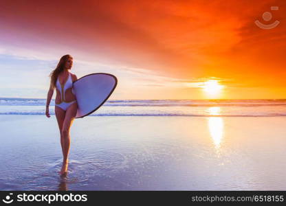 Surfer woman on beach at sunset. Beautiful surfer woman on the beach at sunset