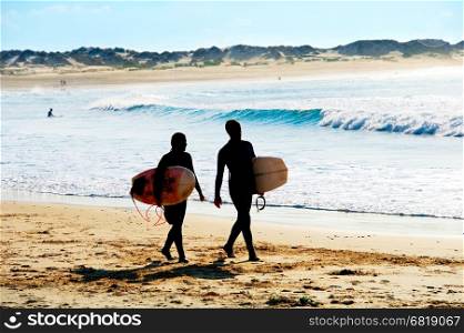 Surfers couple walking on the ocean beach