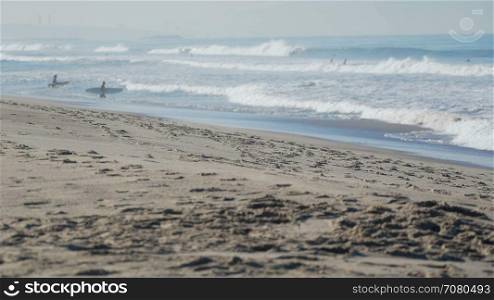 Surfers wade into ocean near the Santa Monica Pier.