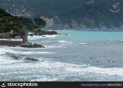 Surfers waiting for a wave in rough seas outside the harbour at Ventigmilia in northern Italy