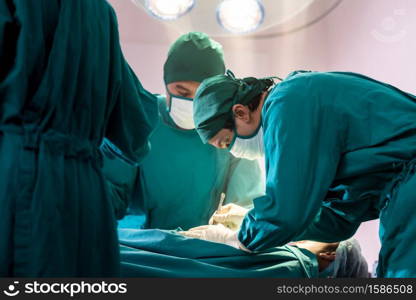 Surgeon doctor and nurse performing Surgical Operation to patient with his team in Operating Room OR. Medical health care Surgery concept.