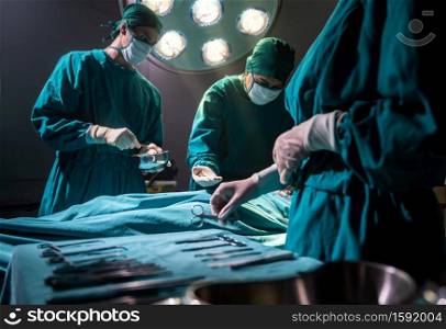 Surgeon doctor asking surgical equipment from Operating room nurse with Medical Team Performing Surgical Operation in Operating Room OR. Medical health care Surgery concept.