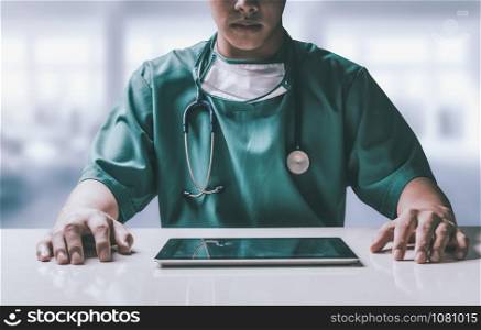 Surgeon doctor sitting at table with tablet computer in hospital office. Medical healthcare staff and doctor service.