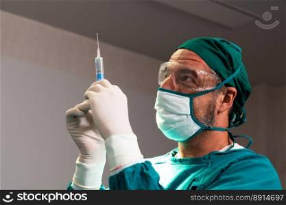 Surgeon fill syringe from medical vial for surgical procedure at sterile operation room. Doctor in full protective wear for surgery prepare anesthesia injection for his patient. Surgeon fill syringe from vial for surgical procedure at sterile operation room.