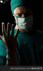 Surgeon put on protective surgical sterile gloves and mask as preparation before perform surgical operation in the surgery room. Surgery preparation concept for medical use.. Surgeon put on protective surgical sterile glove and mask before perform surgery