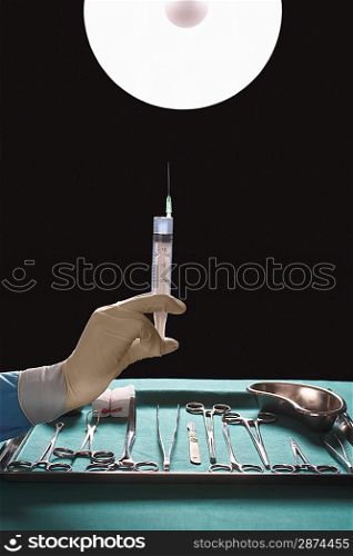 Surgeons hand holding syringe near medical equipment in operating theatre