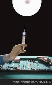 Surgeons hand holding syringe near medical equipment in operating theatre