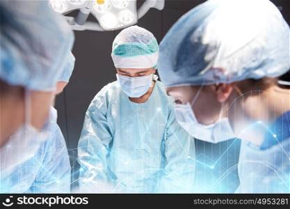 surgery, healthcare, medicine and people concept - group of surgeons at operation in operating room at hospital with virtual diagram projection. group of surgeons in operating room at hospital