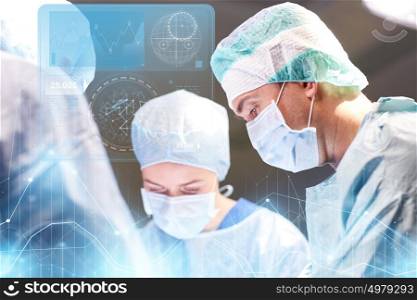 surgery, healthcare, medicine and people concept - group of surgeons at operation in operating room at hospital with diagram and virtual screen projection. group of surgeons in operating room at hospital