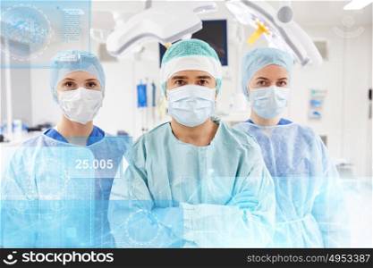 surgery, healthcare, medicine and people concept - group of surgeons in operating room at hospital with diagram and virtual screen projection. group of surgeons in operating room at hospital