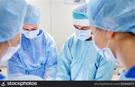 surgery, medicine and people concept - group of surgeons at operation in operating room at hospital. group of surgeons in operating room at hospital. group of surgeons in operating room at hospital