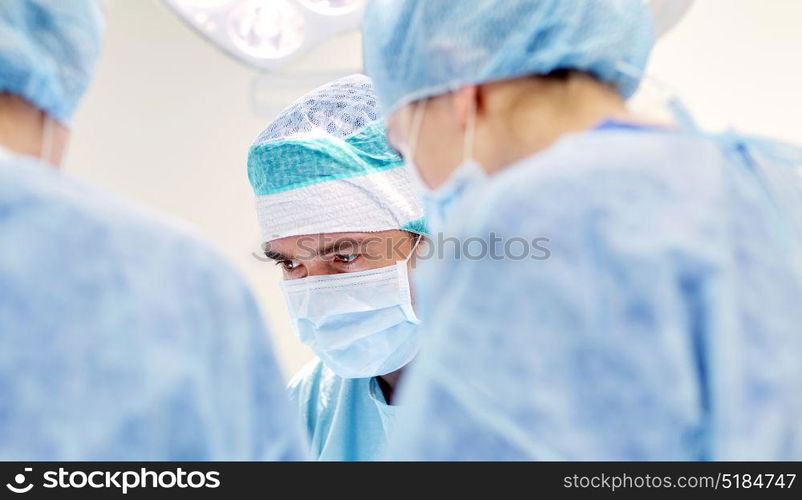 surgery, medicine and people concept - group of surgeons at operation in operating room at hospital. group of surgeons in operating room at hospital