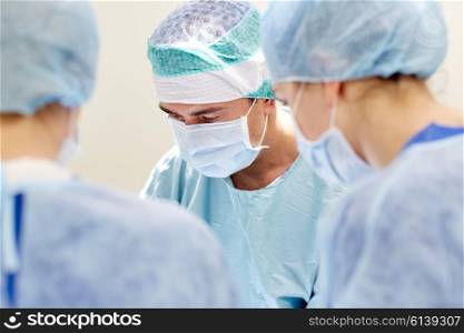 surgery, medicine and people concept - group of surgeons at operation in operating room at hospital