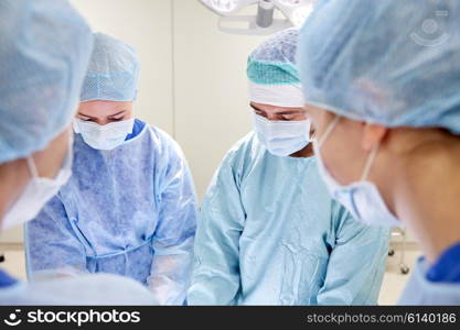 surgery, medicine and people concept - group of surgeons at operation in operating room at hospital