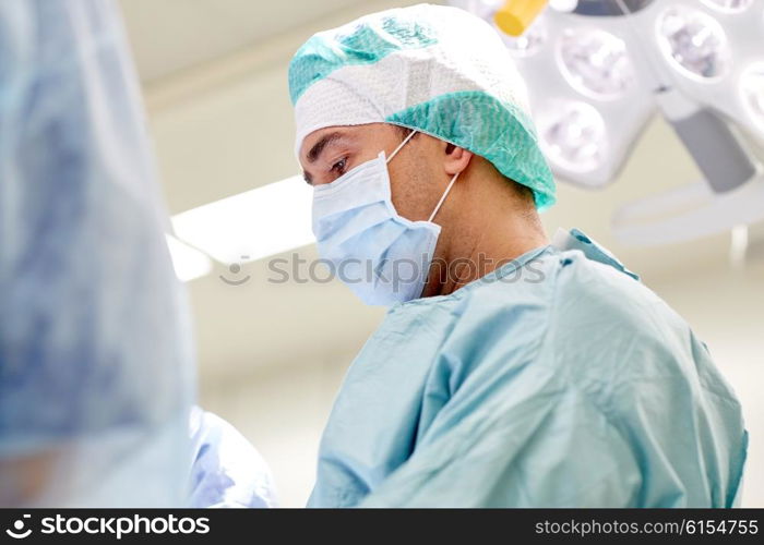 surgery, medicine and people concept - group of surgeons at operation in operating room at hospital