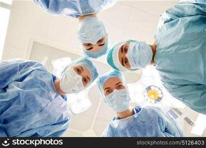 surgery, medicine and people concept - group of surgeons in operating room at hospital looking into camera. group of surgeons in operating room at hospital