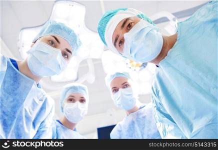 surgery, medicine and people concept - group of surgeons in operating room at hospital looking into camera. group of surgeons in operating room at hospital