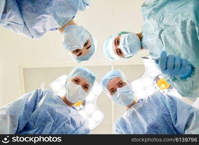 surgery, medicine and people concept - group of surgeons in operating room at hospital looking into camera