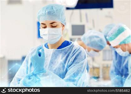 surgery, medicine and people concept - surgeon wearing medical gloves in operating room at hospital. surgeon in operating room at hospital