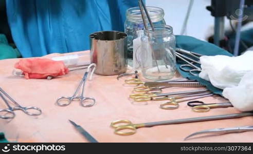 Surgical instruments and tools including scalpels, forceps, scissors and tweezers lying on the table in disorder in operating room after successful surgical operation.