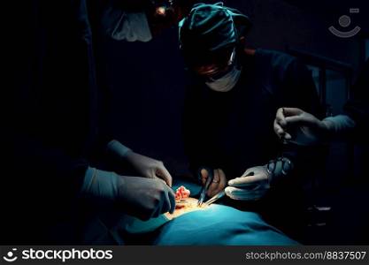 Surgical team performing surgery to patient in sterile operating room. In a surgery room lit by a l&, a professional and confident surgical team provides medical care to an unconscious patient.. Surgical team performing surgery to patient in sterile operating room.