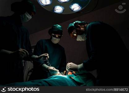 Surgical team performing surgery to patient in sterile operating room. In a surgery room lit by a l&, a professional and confident surgical team provides medical care to an unconscious patient.. Surgical team performing surgery to patient in sterile operating room.