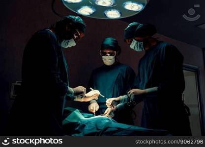Surgical team performing surgery to patient in sterile operating room. In a surgery room lit by a lamp, a professional and confident surgical team provides medical care to an unconscious patient.. Surgical team performing surgery to patient in sterile operating room.