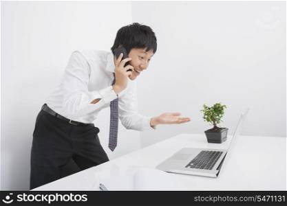 Surprise businessman using cell phone and laptop in office