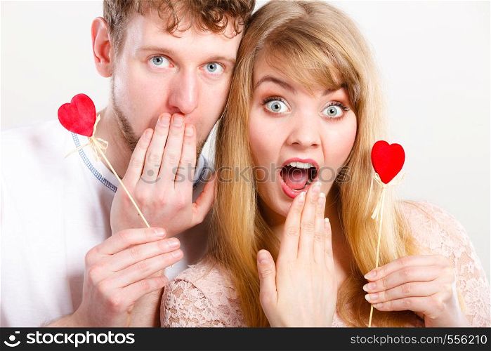 Surprise concept. Young lovers girlfriend boyfriend in big emotional shock. Female and male amazed holding little hearts on sticks.. Boy and girl in big shock.