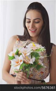 Surprise young Indian woman holding bunch of flowers at home