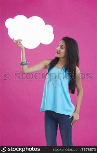 Surprise young woman holding thought bubble over pink background