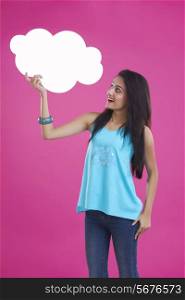 Surprise young woman holding thought bubble over pink background