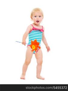 Surprised baby girl in swimsuit with pinwheel