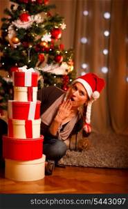 Surprised beautiful woman near Christmas tree looking on tower of present boxes &#xA;