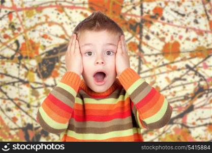 Surprised blond child with a painted background in orange