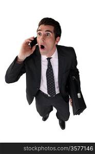 Surprised businessman with telephone and briefcase